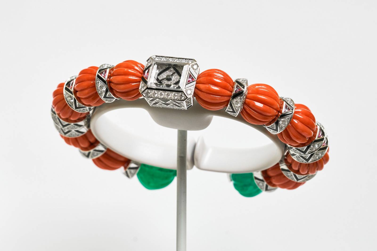 LE VOYAGE RECOMMENCÉ COPTOS⼿鐲腕錶，選用⼀組珊瑚圓珠，頂端鑲飾祖母綠，並綴以紅碧璽及縞瑪瑙。 （圖片來源：卡地亞）